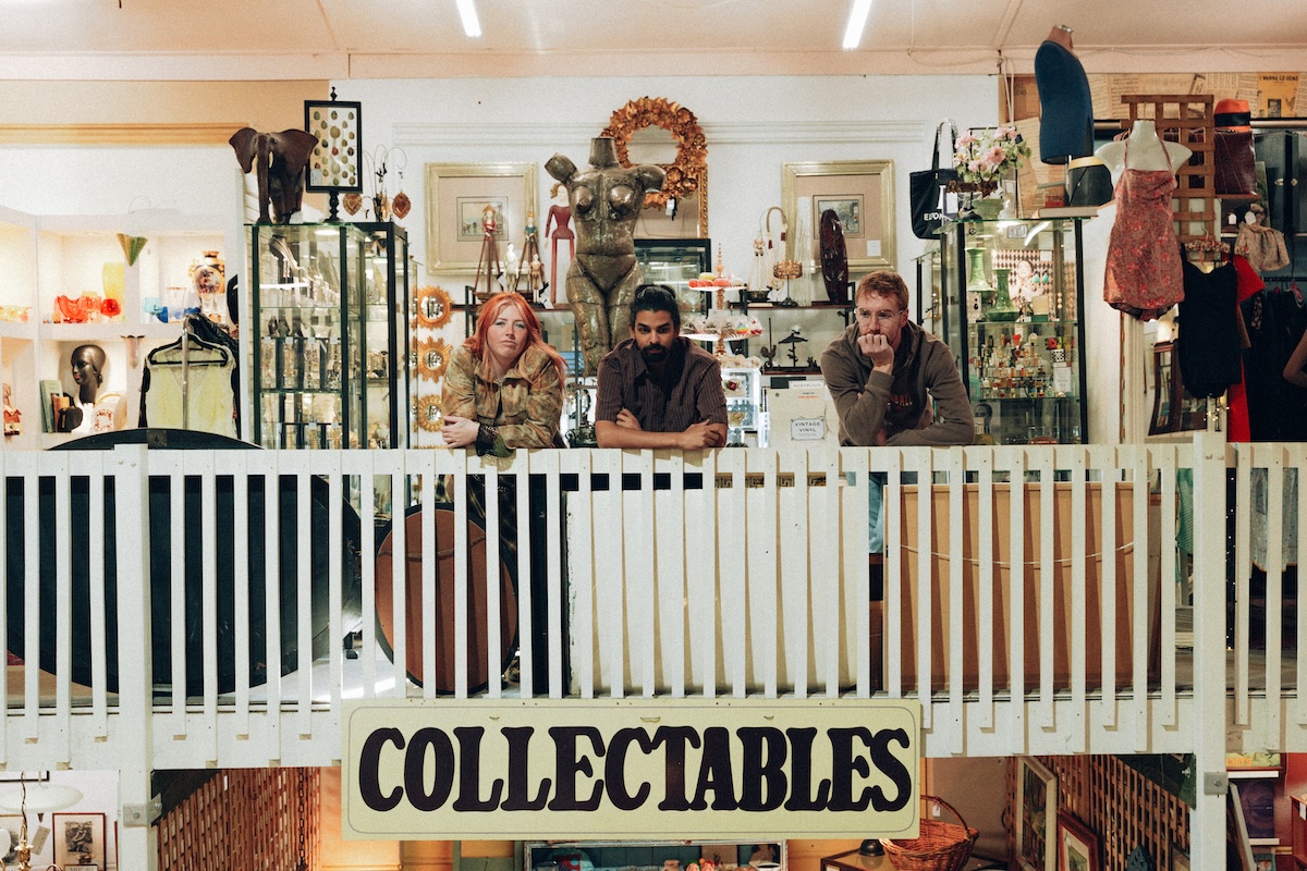 Indie band Club Halifax leaning over a balcony in a vintage collectibles shop.